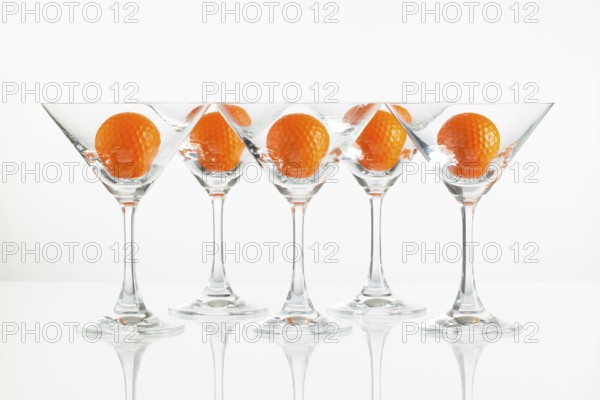 Five glasses of champagne and golf equipments on the glass desk