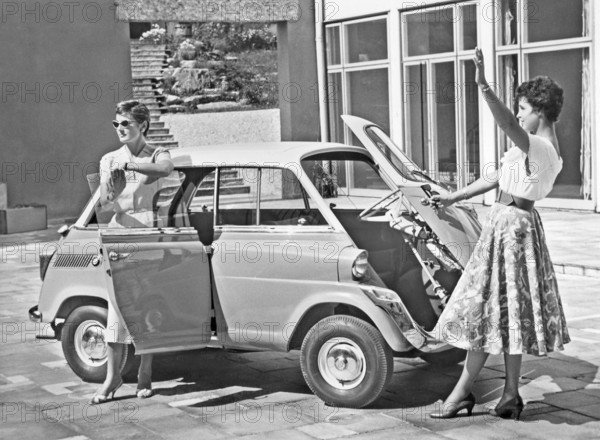Driving in the 1950s. Two young women is standing beside a car model BMW 600. A micro car model with the front door really in front. 1958
