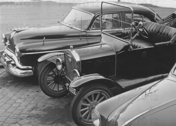 In the 1950s. Cars are parked beside each other and they are from different eras. An american Oldsmobile, model ca 1951-1952 and a Model T Ford. Sweden 1957