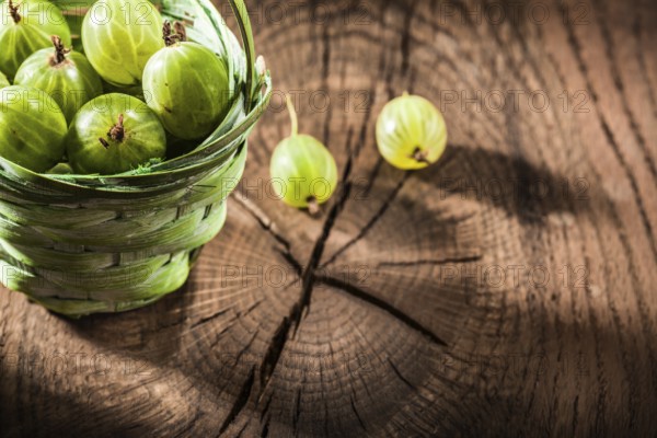 Fresh gooseberries in basket on vintage wooden board