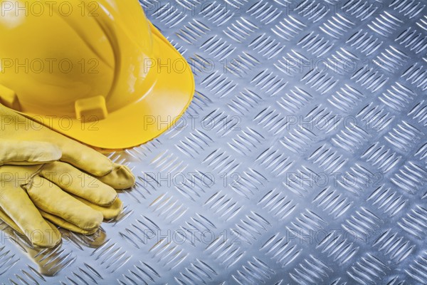 Protective leather gloves building helmet on channeled metal sheet construction concept