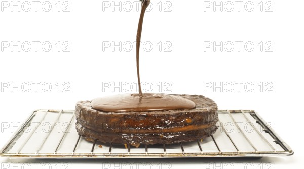 Closeup of chocolate icing pouring over Sacher torte towards white