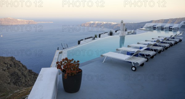 Roof garden of a holiday resort hotel against the ocean at sunset. Oia village, Santorini Island, Greece. Landscape greek islands
