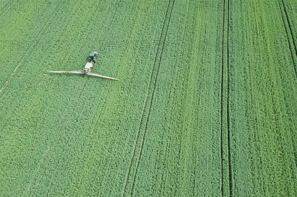 Aerial view Farm machinery spraying chemicals on the large green field, agricultural spring background