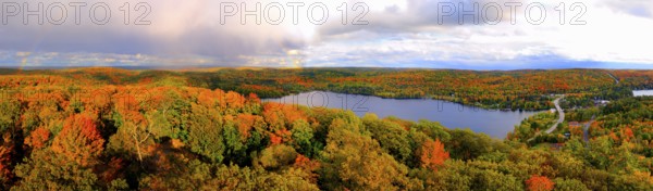 Aerial panoramic view of Lake of Bays and colorful fall forest during sunset with a trace of a rainbow. Dorset Ontario Canada