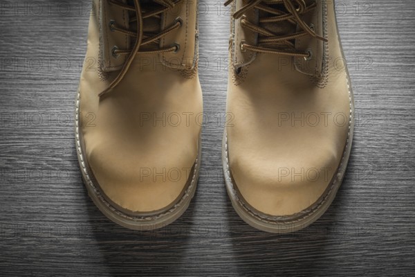 Pair of waterproof working boots on wooden board