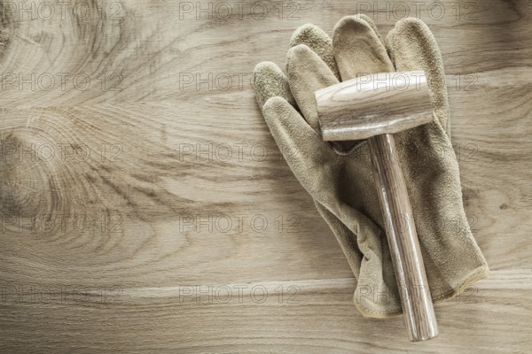 Safety gloves lump hammer on wooden board