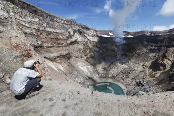 KAMCHATKA, RUSSIA, JULY 21, 2013: Tourist in the crater active Gorely Volcano shoot of the volcano acting fumarole and crater lake. Russia, Far East, Kamchatka Peninsula