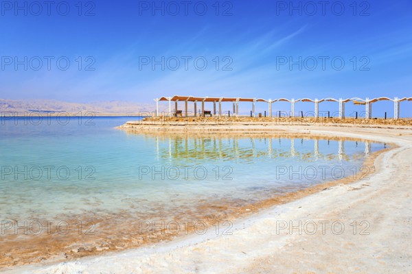 The drainless salt lake in the Middle East. Dead Sea. Israel. Evaporated salt forms ?rystals on the surface of the water. Special awning on the beach to protect from the sun