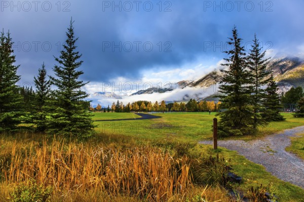 Canada, Banff. Rocky mountains in the clouds. Sports field in the vicinity of the city. Cool and Wet Early Autumn. Concept of active, eco-friendly and photo-tourism