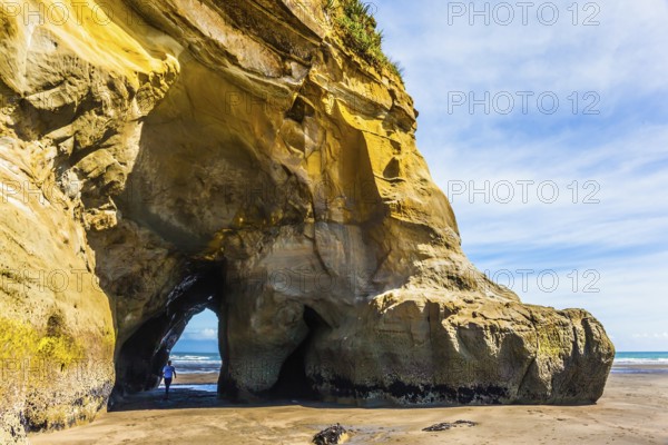 Coastal arches and rocks to the ocean tide. The concept of active and phototourism. The Pacific coast, New Zealand, North Island