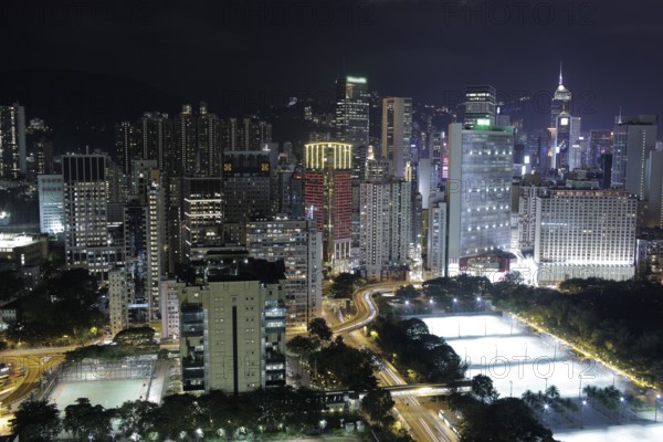Illuminated Hong Kong. Night city view with concrete jungle, road interchange and football fields