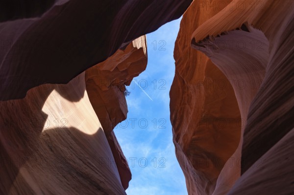 A picture of the rock formations of the Lower Antelope Canyon, while a plane is flying in the blue sky