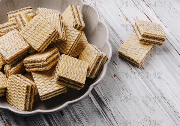 Food, Crisp layered wafers are neatly arranged in a bowl, their patterns creating an inviting look. A few wafers are placed beside the bowl on a rustic wooden table