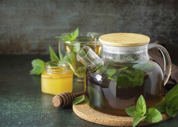 Therapeutic herbal green tea. Hot tea with honey mints in a glass teapot on a stone table. Copy space