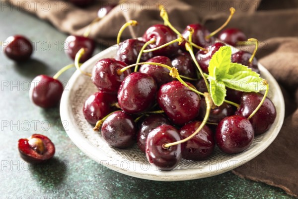 Ripe organic berry. Fresh Red sweet cherry on plate on a dark stone tabletop