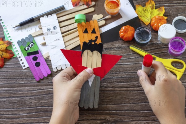 Instructions, step 6. Halloween ghost and vampire toy gift stics puppets on wooden table. Handmade. Project of children's creativity, handicrafts, crafts for kids