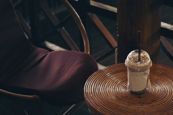 A cozy cafe setting with an iced coffee on a round rattan table and chair