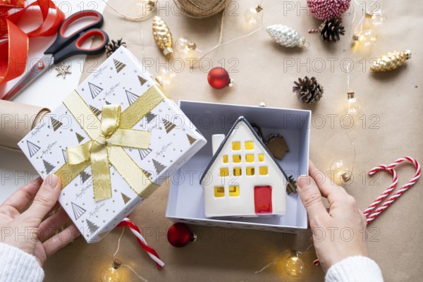 Key to house with keychain on cozy home in gift box with Christmas decor packaging. Pack present for New Year, Christmas. Building, project, moving to new house, mortgage, rent, purchase real estate