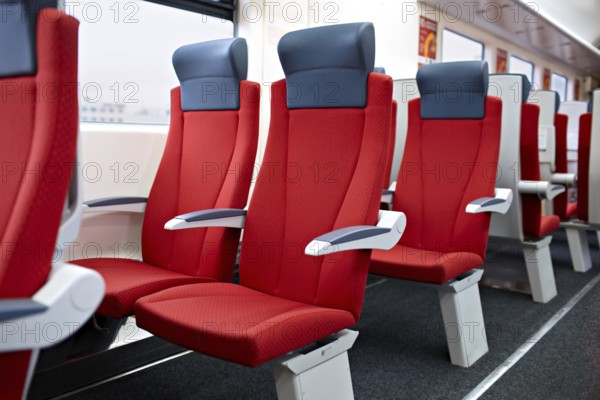 An interior view of a modern high speed train. Red chairs