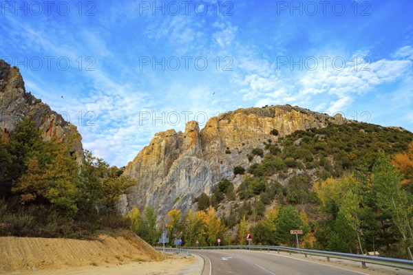The trip to Spain. Asphalt highway passes among steep cliffs. The sky is covered with light clouds
