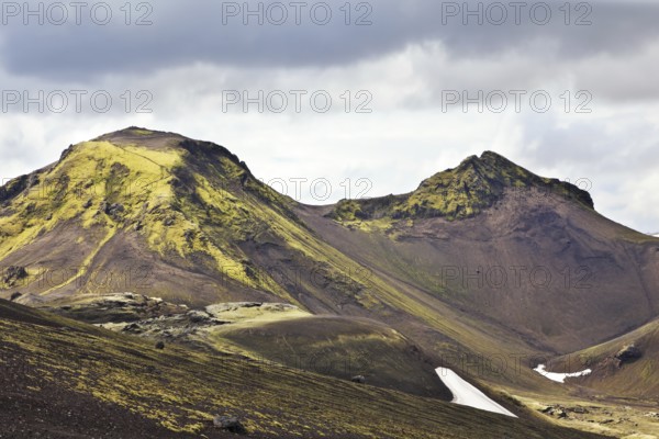 National Park Landmannalaugar in July. Green and pink mountain slopes and snowy white residues from last winter