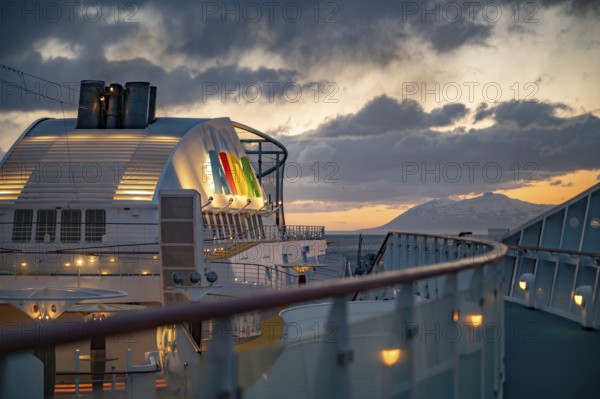 Illuminated AIDA Logo attached to AIDA Bella ship with fence and boat deck in front in the evening