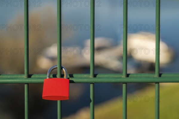 Love lock and grid of the lift bridge Walsum in Duisburg, North Rhine-Westphalia, Germany, with some blurry boats in the background