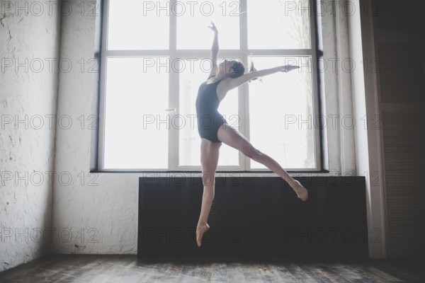 Plasticity slim woman dancing near window. Professional dancer enjoy dance. Lady Dancer Training Modern Ballet In Class. Contemporary dance performer. Daylight, silhouette beautiful body. Dance theme