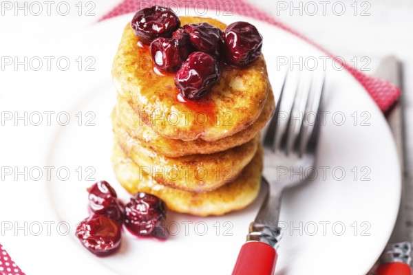 Cheese pancakes with cherry jam on the plate