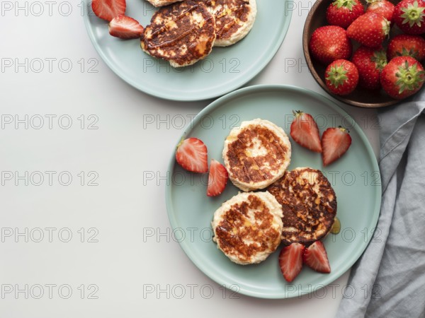 Sweet cheese pancakes on plate served strawberries. Cottage cheese pancakes, syrniki, ricotta fritters, curd fritters. Top view or flat lay. Copy space for text or design