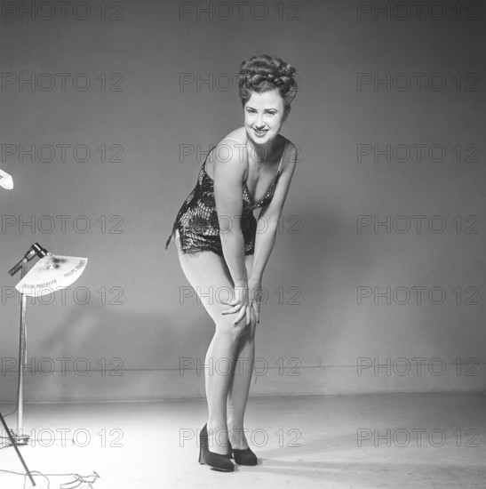 Sweden 1948. Kristoffersson Ref AT46-9 Woman in photo studio back in the day. A young woman with long slender legs, standing in a short dress poses and smiling at the camera. She has her hair done in the typical 1940s manor and on her feet she has high-heeled black shoes. Kristoffersson ref AT44-3
