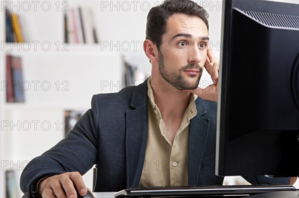 Surprised man looking at a computer screen, thinking about the job at hand