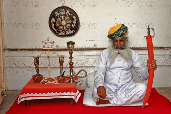 Jodhpur, Rajasthan, North India, Asia, Seated man with a sword and traditional clothes in a decorative room, India