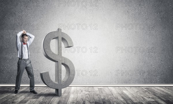 Young furious businessman going to crash with hands stone dollar symbol