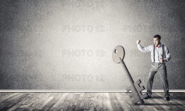 Determined businessman in concrete interior breaking with fist stone key figure