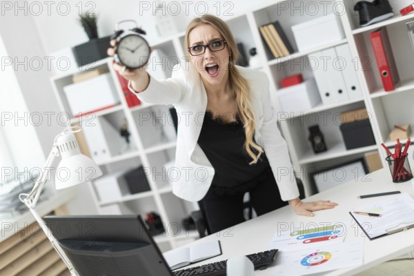 A beautiful young blonde girl in a white jacket and black blouse is working in the office. photo with depth of field