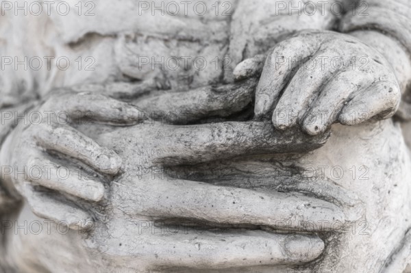 Detail of a marble statue with hands of child and woman together