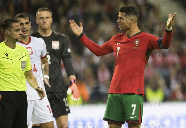 Football match, captain Cristiano RONALDO CR7 Portugal right, energetically protesting with raised arms and hands towards referee Donatas RUMSAS Lithuania, in the background left Jakub KIWIOR Poland 14 also protesting and goalkeeper Marcin BULKA Poland, Estadio do Dragao, Porto, Portugal