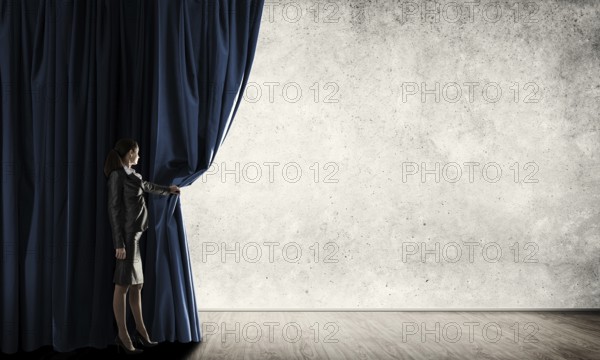 Young woman with megaphone in business suit opening color curtain
