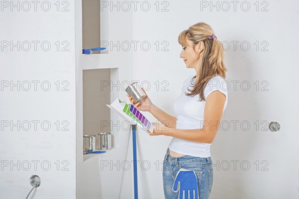 Female painter holding and looking on color palette with paint