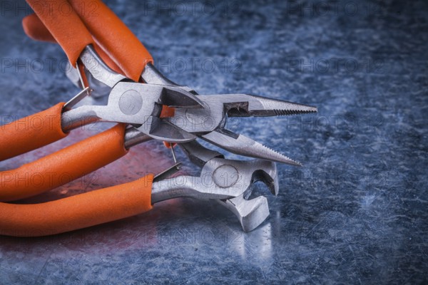 Set of insulated electric pliers nippers on scratched metallic background