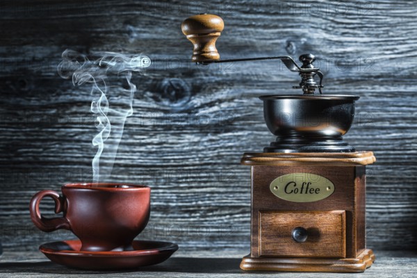 Vintage wooden coffee mill and brown cup with steam