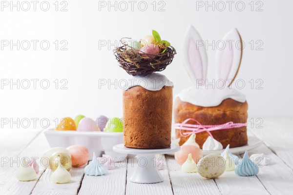 In the foreground an Easter cake decorated with a nest on the top. Painted eggs in the nest. In the background is another Easter cake with bunny ears