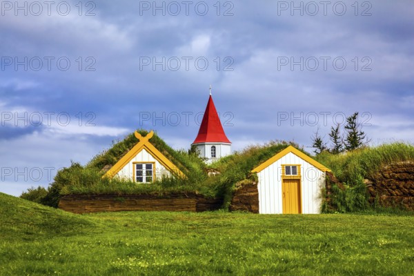 Church bell tower with red gabled roof. The old village of houses covered with turf and grass. Ethnographic Museum-estate Glaumbaer, Iceland. The concept of the historical and cultural tourism