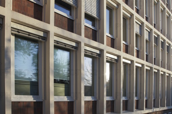 Sunlight reflecting on a modern building facade with rows of windows and venetian blinds, creating an interesting pattern of light and shadow, Bottrop, NRW, Germany