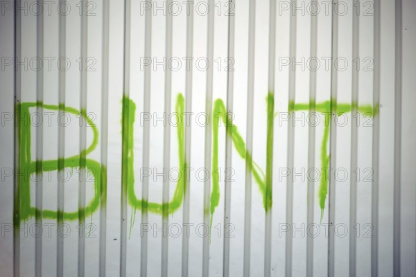 The detail of a corrugated iron façade colourfully painted with the slogan
