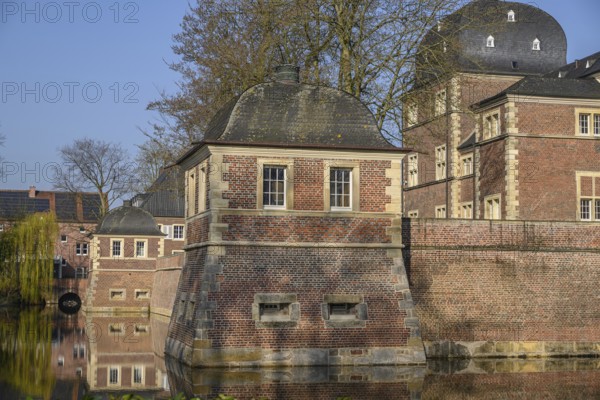 A pavilion and a brick castle reflected in the calm waters of a moat, ahaus, münsterland, germany