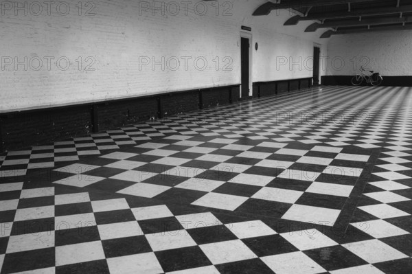 Chequered floor covering in front of a white house wall, behind it a vintage bicycle, black and white, Renesse, Netherlands