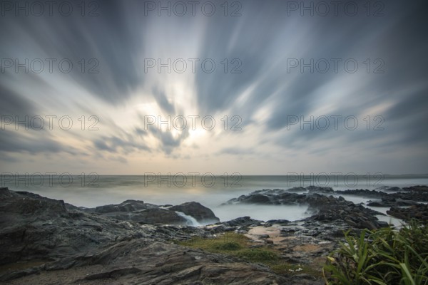 Beach, with lava rocks and vegetation, view of the sea in the evening at sunset. Landscape with clouds in Induruwa, Bentota Beach, Sri Lanka, India